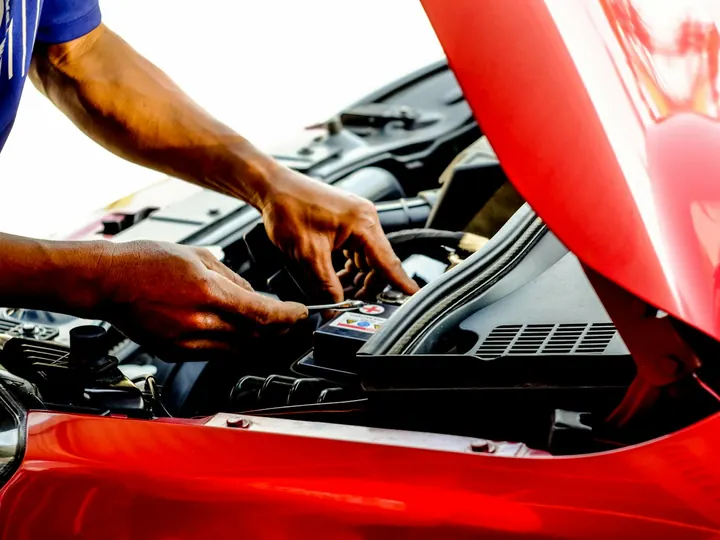 Mâini lucrând la instalația electrică din compartimentul motor