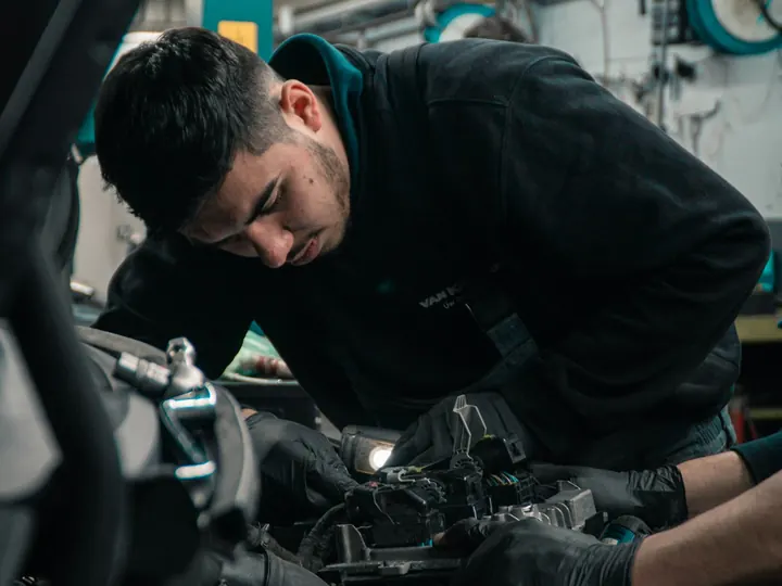 Mecanic lucrând la motorul unei mașini